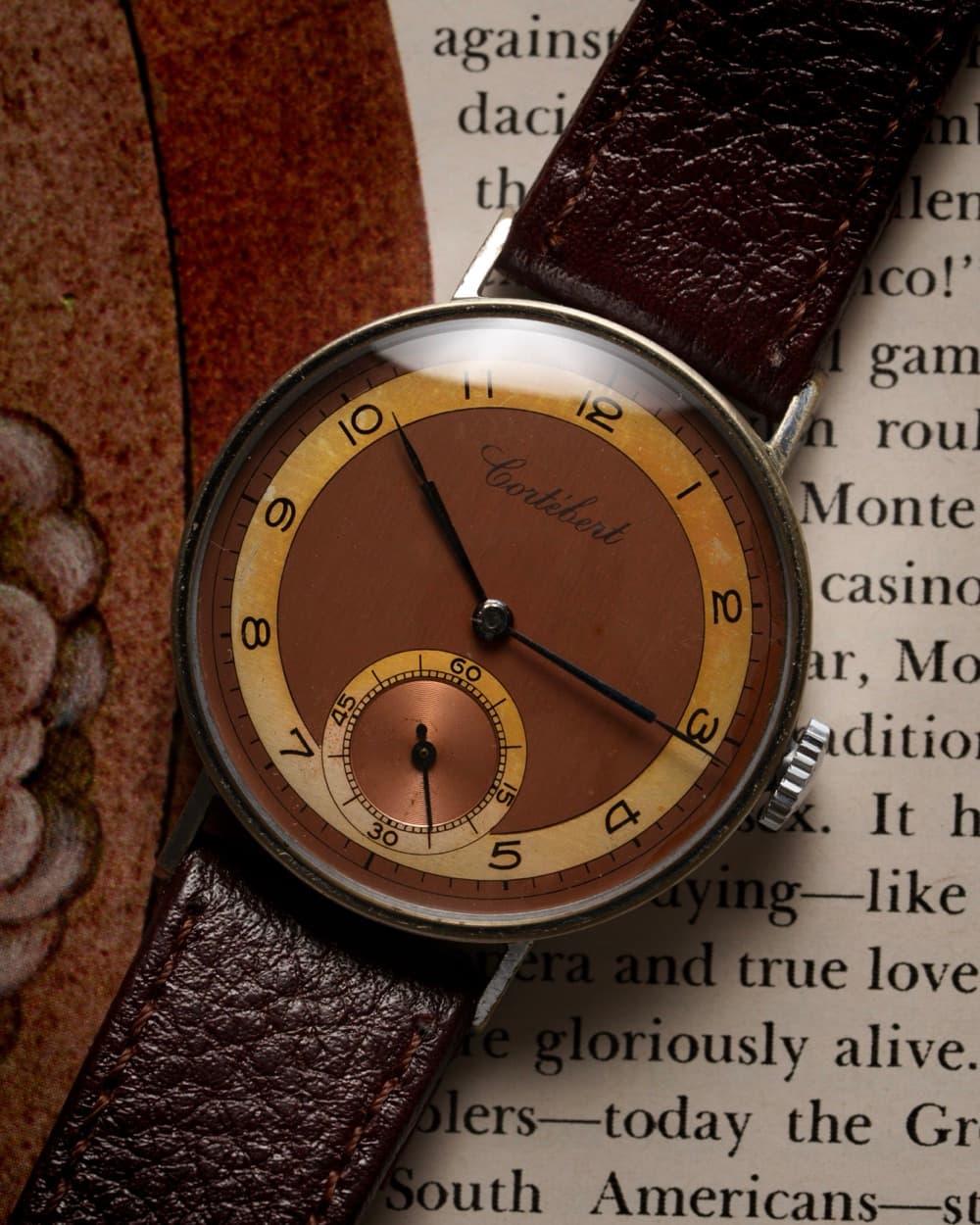 Vintage watch with two-tone copper dial resting on a book page